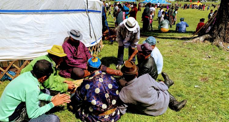 Group of people seated on the ground in traditional attire during a festival.