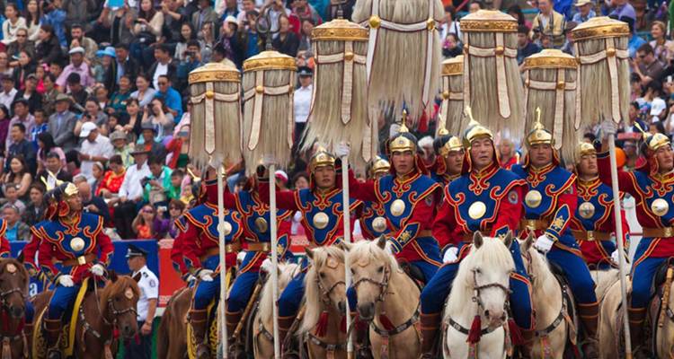 Horse riders in ceremonial dress at a cultural festival.