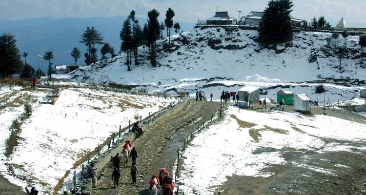 Snowy mountainous path with people and tents.