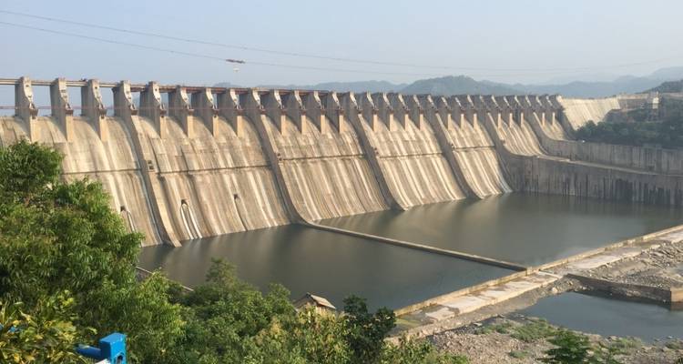 Eine große, beeindruckende Talsperre mit einem ruhigen Wasserspeicher an ihrem Fuß.