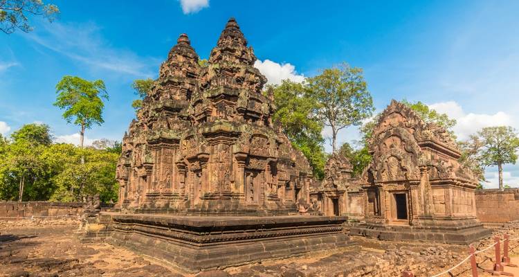 Ancient temple ruins surrounded by lush greenery under a clear blue sky.