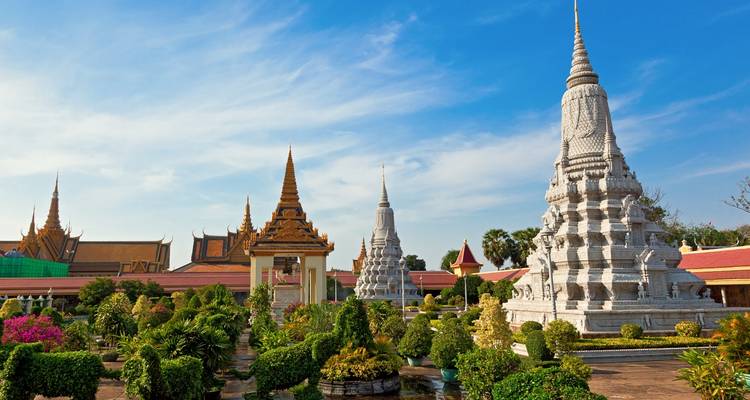 Wide view of a Cambodian temple with white stupas and lush gardens.