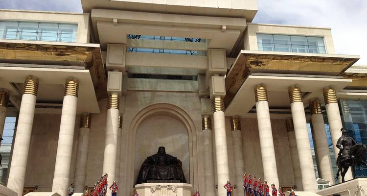 Government building with columns and a large statue in front.