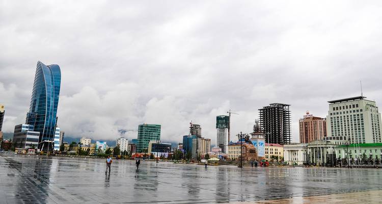 Cityscape with modern buildings and a large plaza in the foreground.