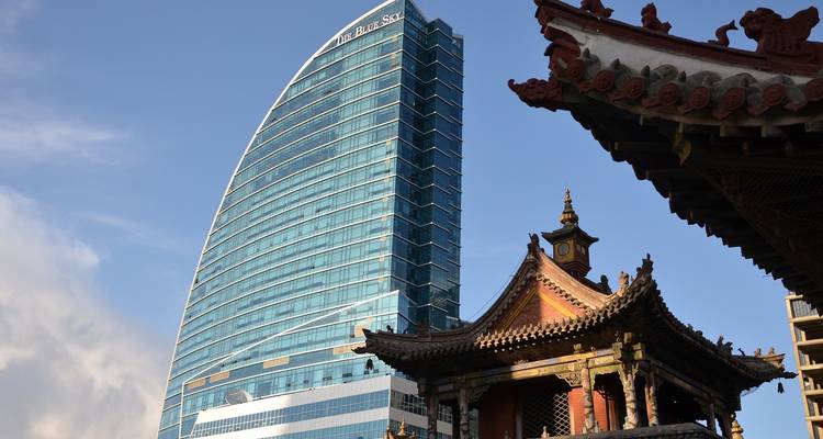 Contrasting skyline of a modern skyscraper and a traditional temple.