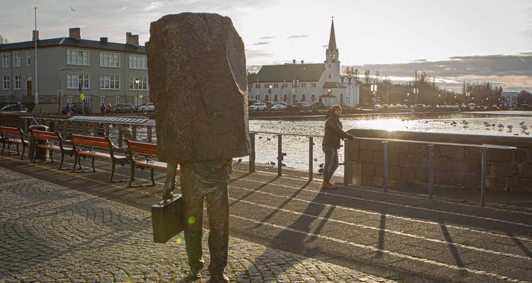 Sculpture d'un homme avec une serviette et des gens près d'un lac à Reykjavik.
