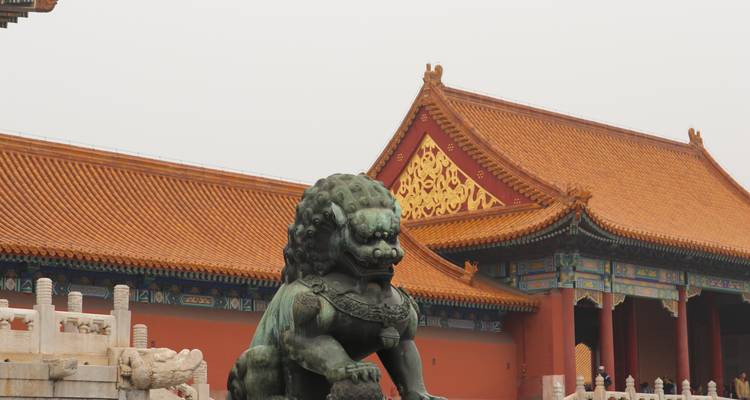 Una estatua de un león custodiando la entrada con arquitectura tradicional china.