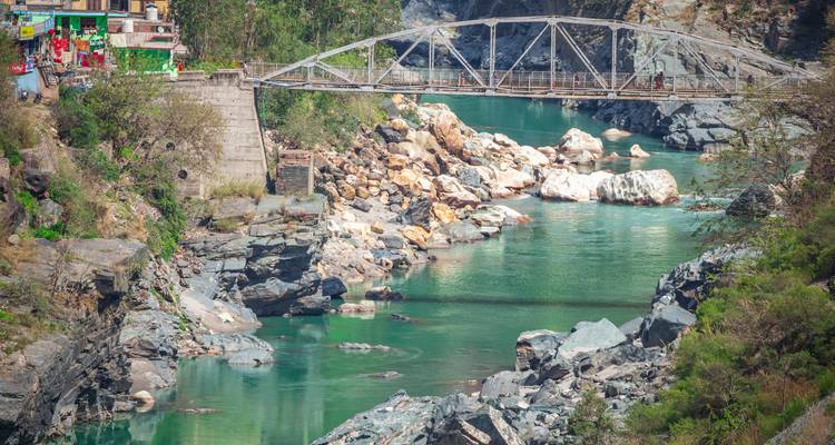 Fluss, der durch eine felsige Landschaft fließt mit einer Metallbrücke darüber.