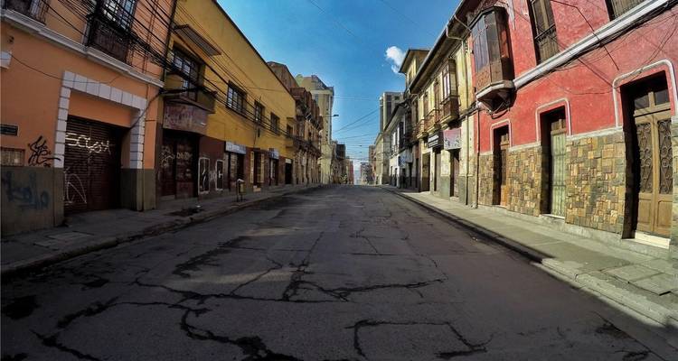 Eine leere koloniale Straße in La Paz mit farbenfrohen Fassaden und rissigem Pflaster, eingefangen im starken Morgenlicht.