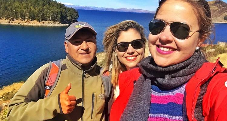 Drei Freunde machen ein fröhliches Selfie neben den tiefblauen Gewässern des Titicaca-Sees.