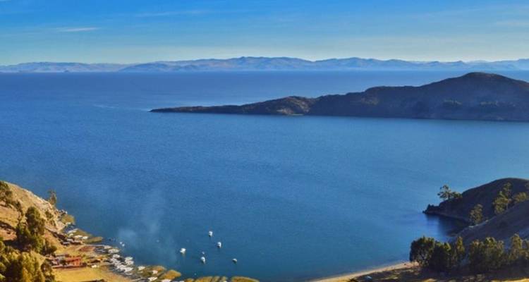 Vue panoramique sur une baie tranquille et des collines ondulantes du lac Titicaca sous un ciel bleu.