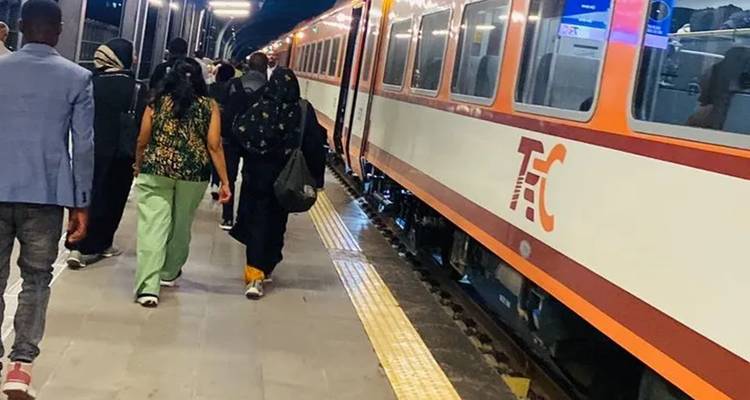 Menschen gehen auf einem Bahnsteig neben einem stehenden Zug.