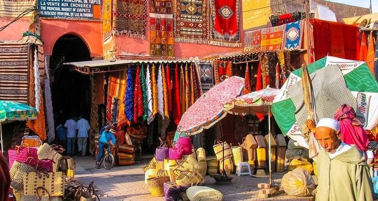 Colorful market scene with rugs and baskets displayed.
