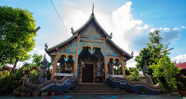 Bunter thailändischer Tempel mit kunstvollen Verzierungen unter einem sonnigen Himmel.