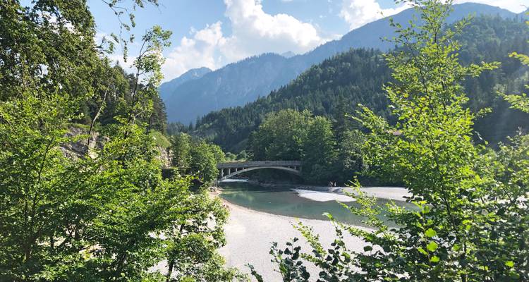 Rivière pittoresque avec un pont et un arrière-plan montagneux.