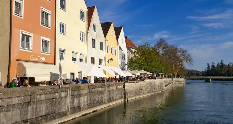 Des gens assis à un café en plein air au bord d'une rivière avec des bâtiments colorés.