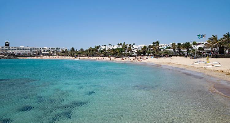 Plage de sable avec des gens et une ville en arrière-plan.