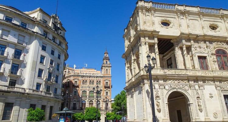 Elegante Bürgerbauten und verzierte Fassaden säumen einen sonnigen Platz im historischen Zentrum von Sevilla.