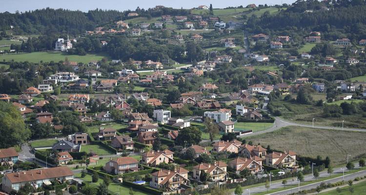 Vue aérienne d'un quartier résidentiel avec des collines en arrière-plan.