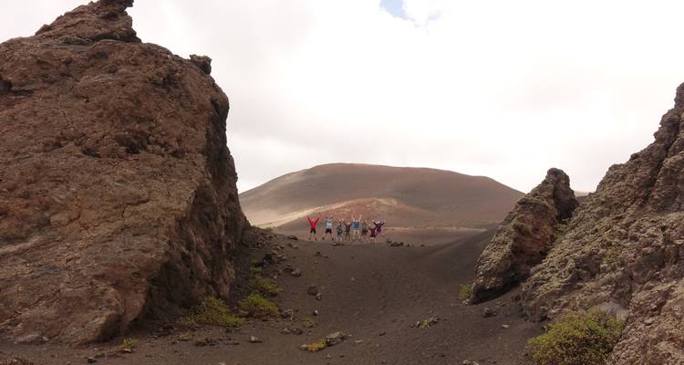 Group of people standing between large volcanic rocks.