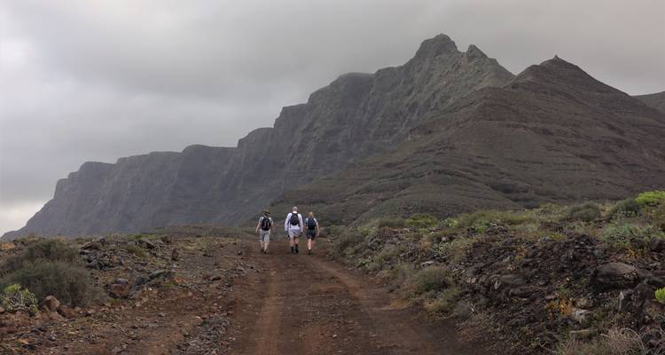 Hikers walking towards a ridge with a rocky landscape.
