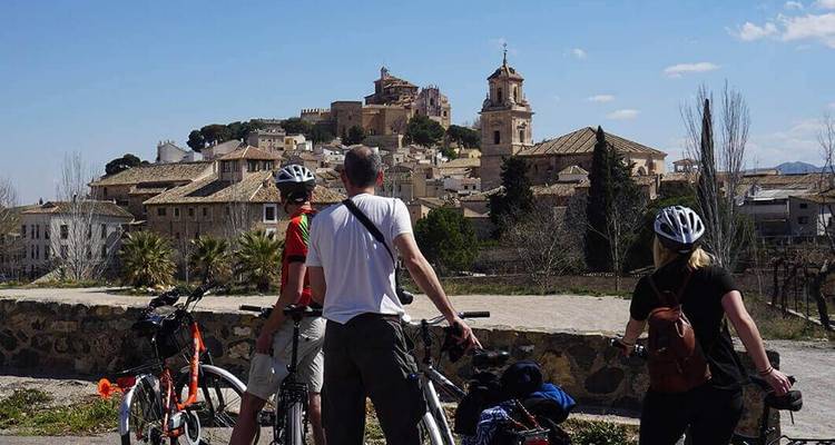 Radfahrer betrachten eine historische Stadt mit Kirchen und alten Gebäuden.
