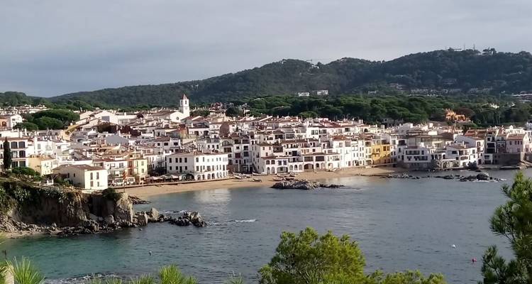 Une ville côtière avec des bâtiments colorés et un arrière-plan vallonné.