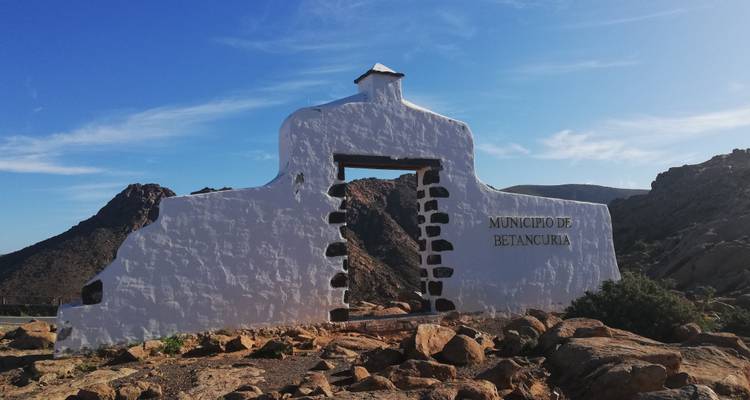 Structure d'entrée monumentale dans un paysage rocheux sous un ciel bleu.