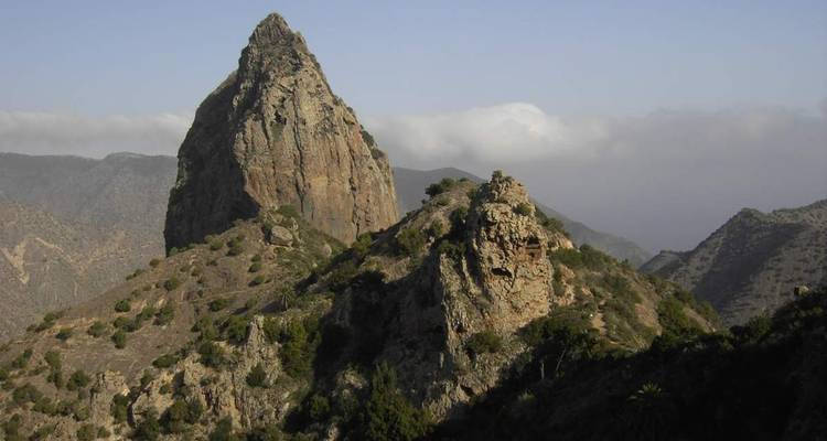 Pic de montagne rocheuse avec des nuages en arrière-plan.
