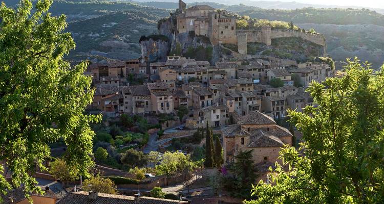 Ville historique perchée avec maisons en pierre et un château.