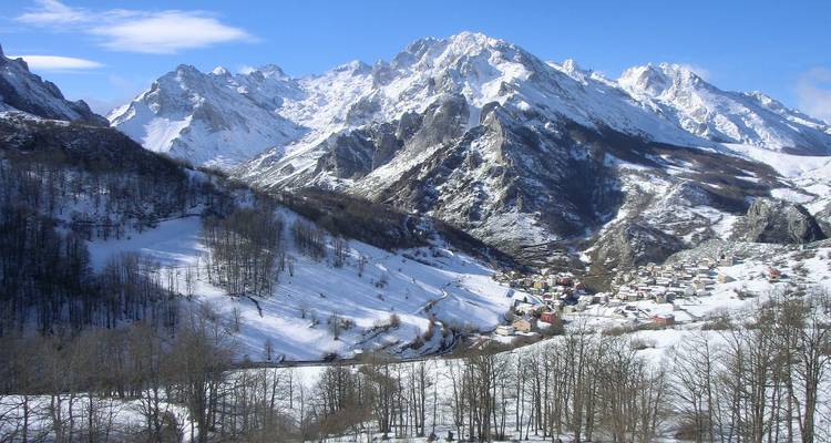 Ein panoramischer Winterblick auf schneebedeckte Berge und ein malerisches Dorf.