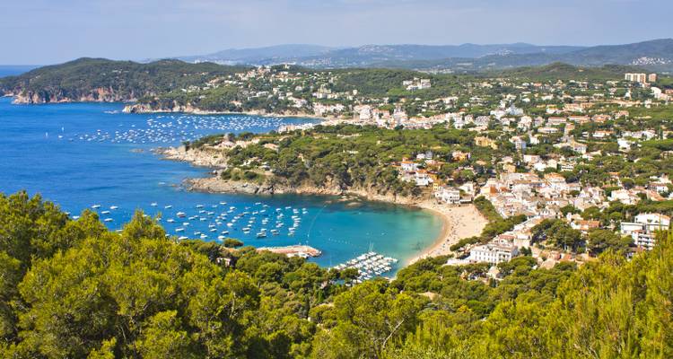 Luftaufnahme einer Küstenstadt mit Stränden und Booten in einer Bucht.