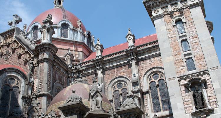 Un gros plan d'un bâtiment historique détaillé et orné avec des dômes et des fenêtres cintrées sous un ciel bleu.