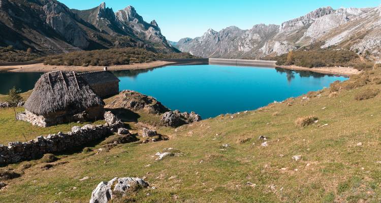 Lac de montagne avec une maison au toit de chaume.