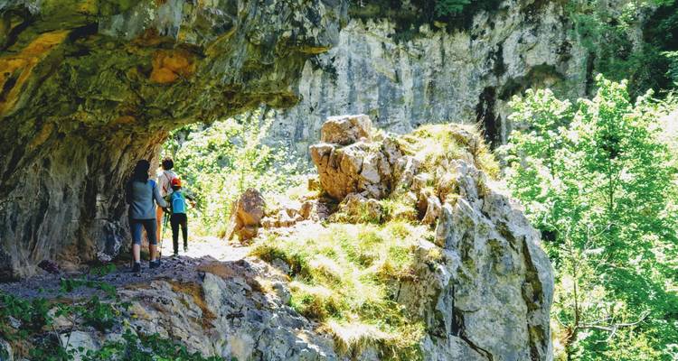 Des randonneurs debout près de l'entrée d'une grotte rocheuse.