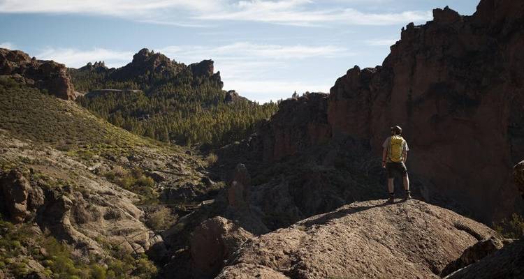 Un randonneur debout sur un paysage rocheux avec vue sur les montagnes.