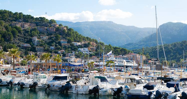 Marina with yachts, surrounded by hills and buildings.