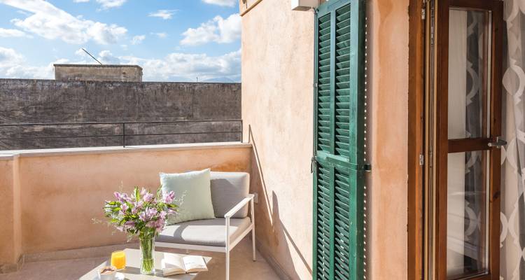 A round table with a chair on a balcony overlooking a cityscape.