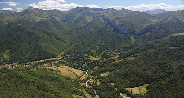 Ein Panoramablick auf ein üppiges, bergiges Tal mit vereinzelten Wolken darüber.