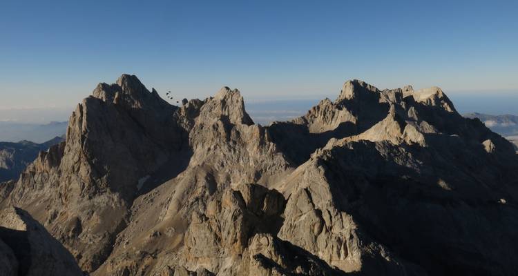 Ein dramatischer Blick auf schroffe Berggipfel unter einem klaren blauen Himmel.