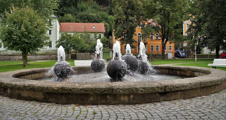 Fontaine décorative dans un parc entourée d'arbres.