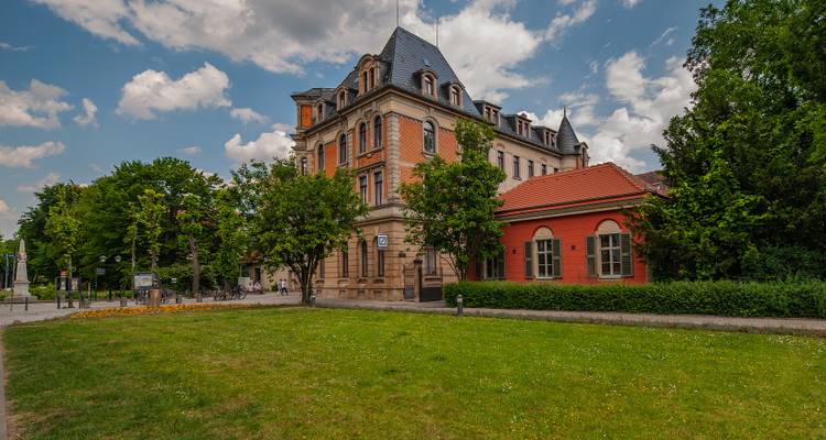 Élégant bâtiment historique avec une façade grandiose et des arbres au premier plan.