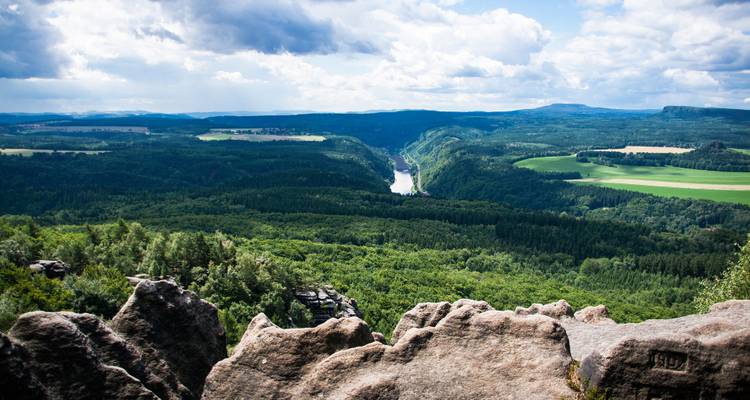 Vue panoramique d'une vallée luxuriante avec une rivière qui serpente à travers.
