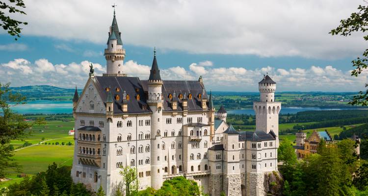 Icónico Castillo de Neuschwanstein con un telón de fondo escénico de colinas y bosque.