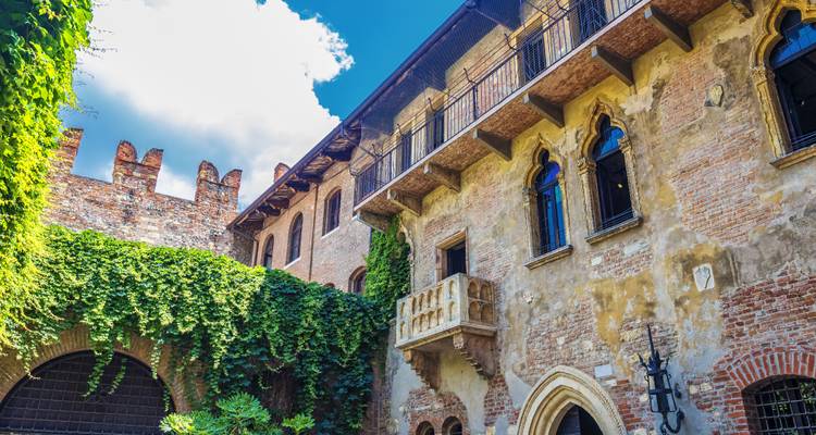 Patio con muros de ladrillo cubiertos de hiedra, y un pequeño balcón de Julieta.