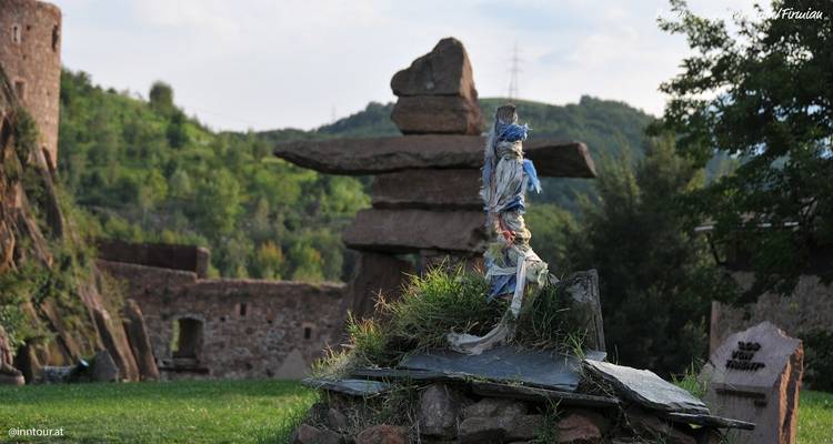 Stone structures and rocks in a green landscape with a hill.