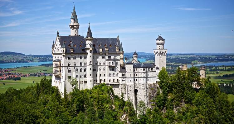 Majestic castle set in lush green hills with a lake in the background.