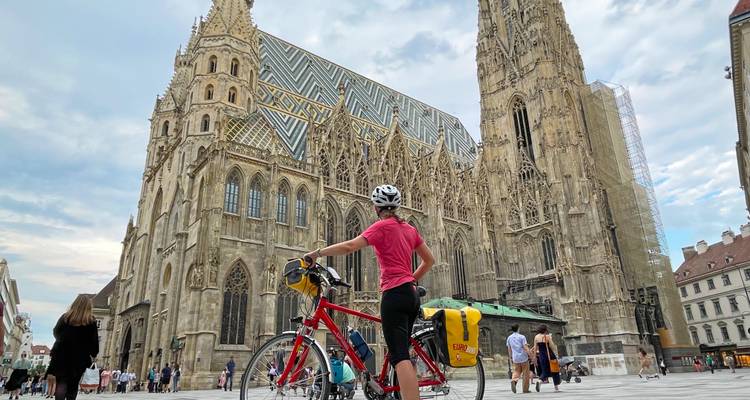 Cycliste avec vélo de randonnée se tient devant la façade ornée de la cathédrale Saint-Étienne à Vienne