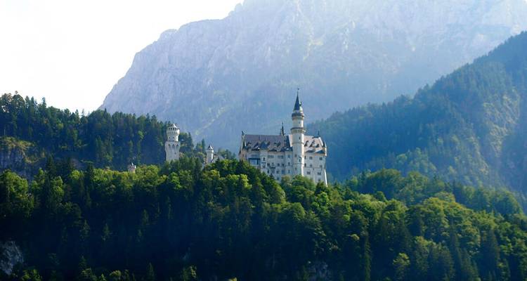 Un château sur une colline entouré de forêts luxuriantes et de montagnes.