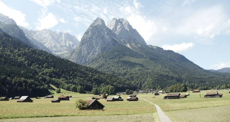 Vallée alpine avec granges dispersées et toile de fond montagnarde spectaculaire.